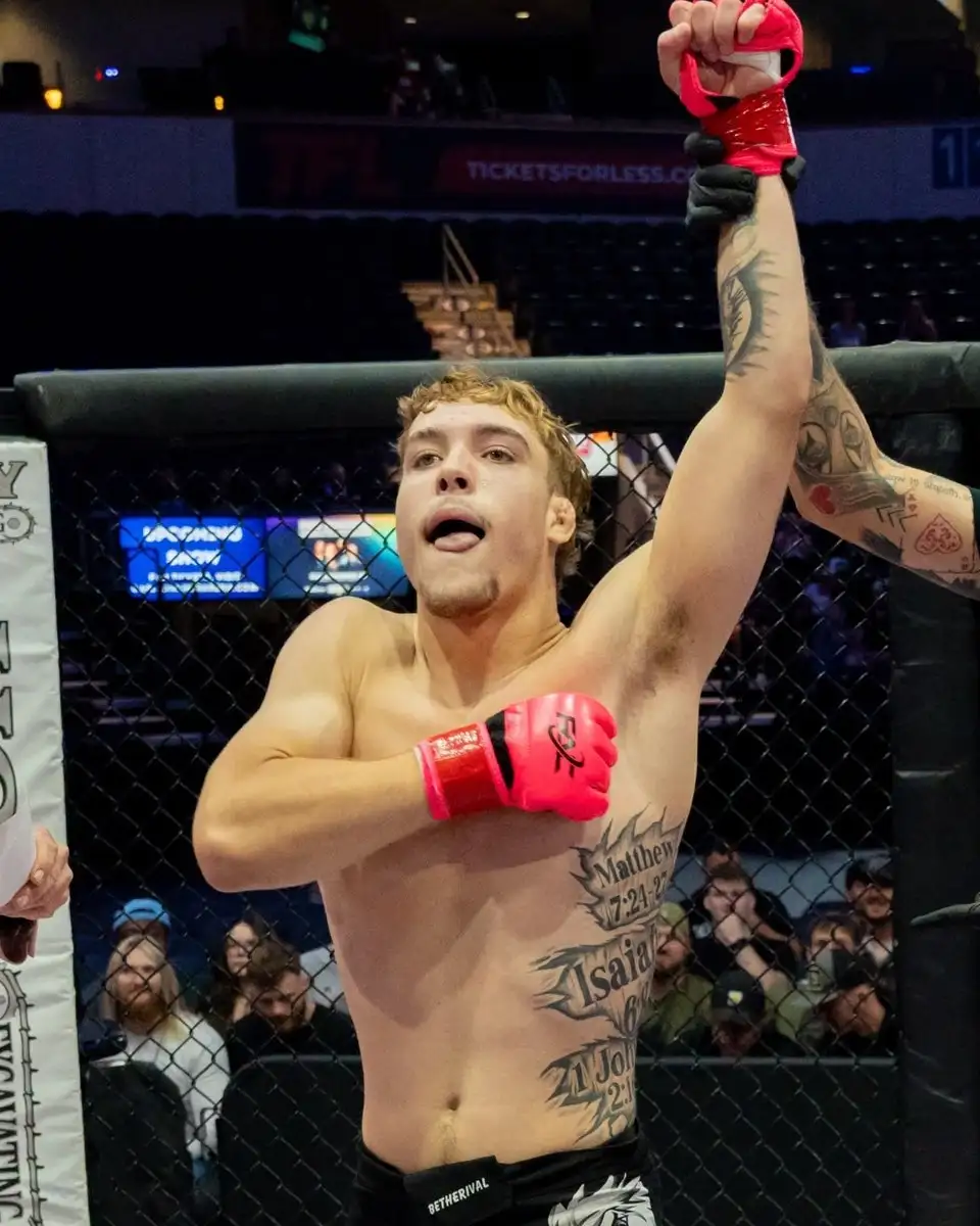 Ethan Huffman, fitness kickboxing coach at Glory MMA & Fitness, with his hand raised after a win