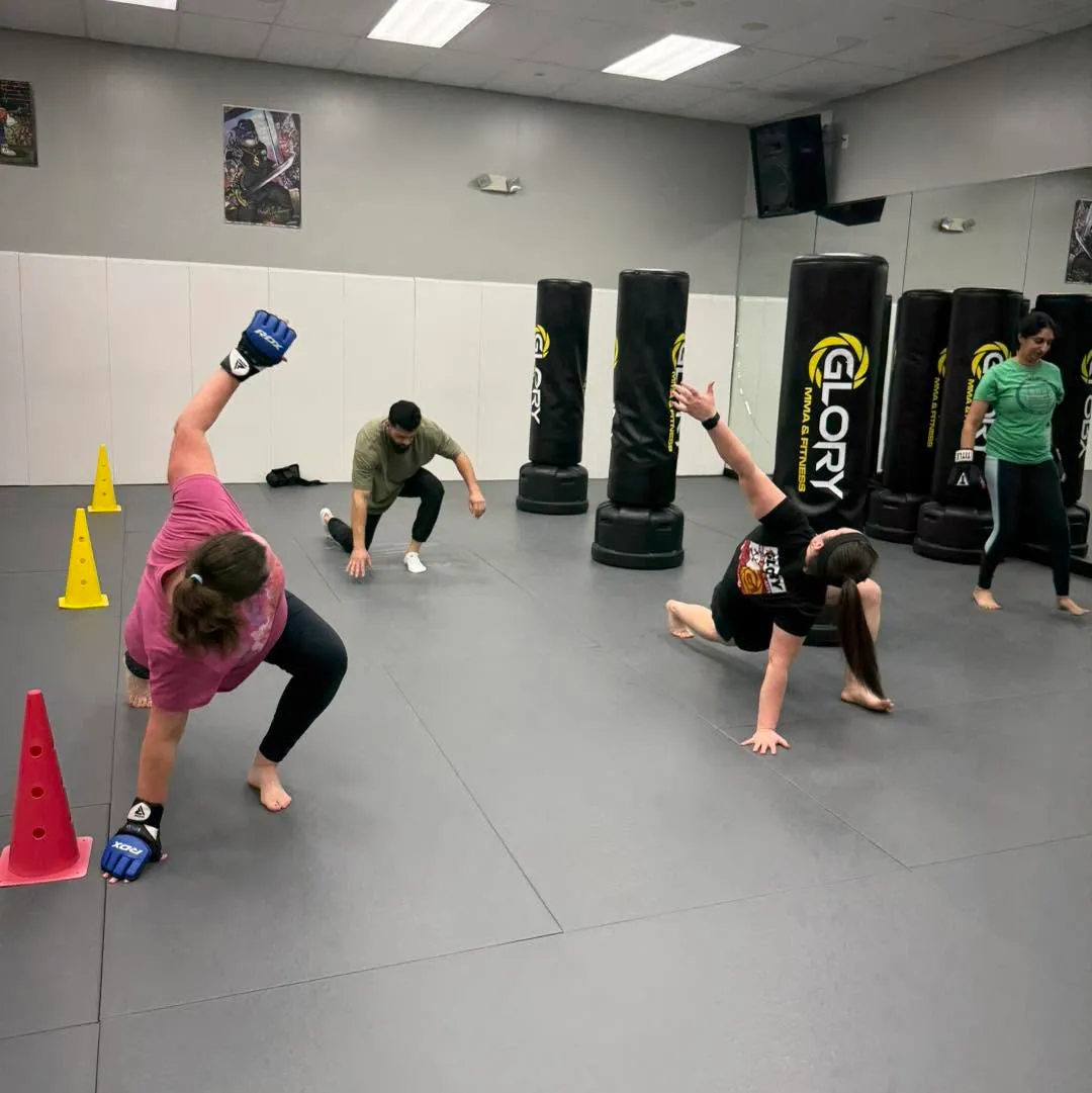 Kickboxing class drilling footwork around cones and Glory heavy bags