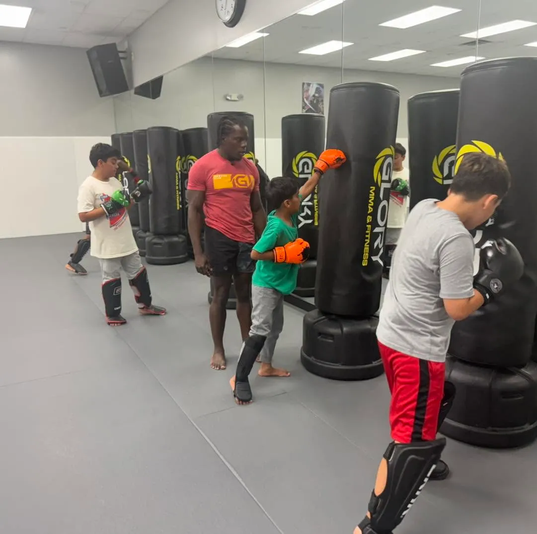 Kids kickboxing on the heavy bags with a coach