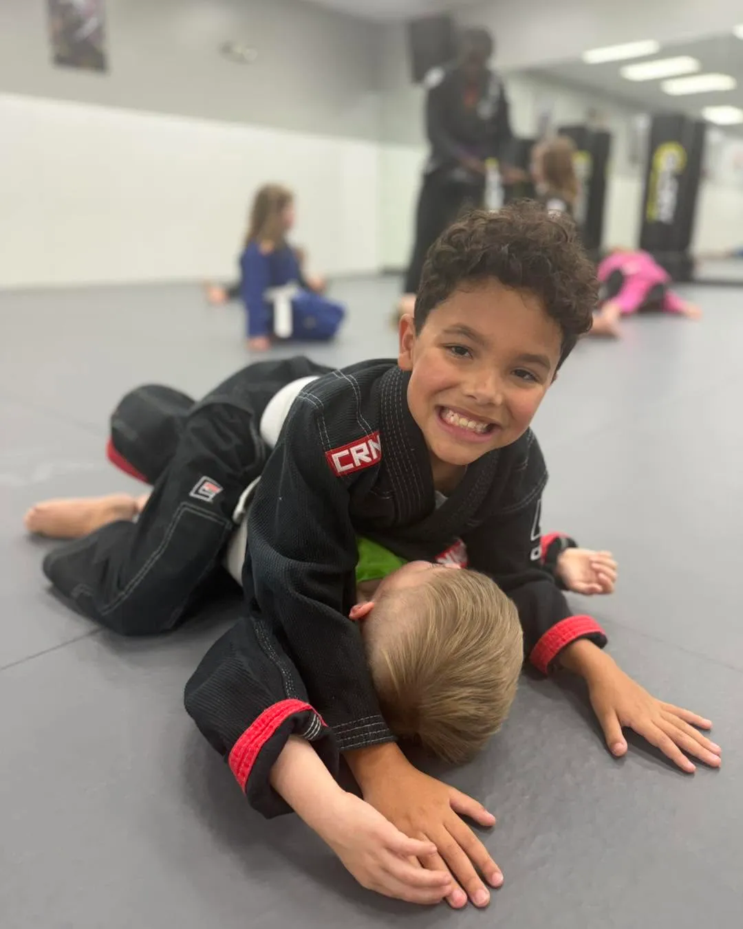 Smiling kid in a black gi during kids jiu-jitsu