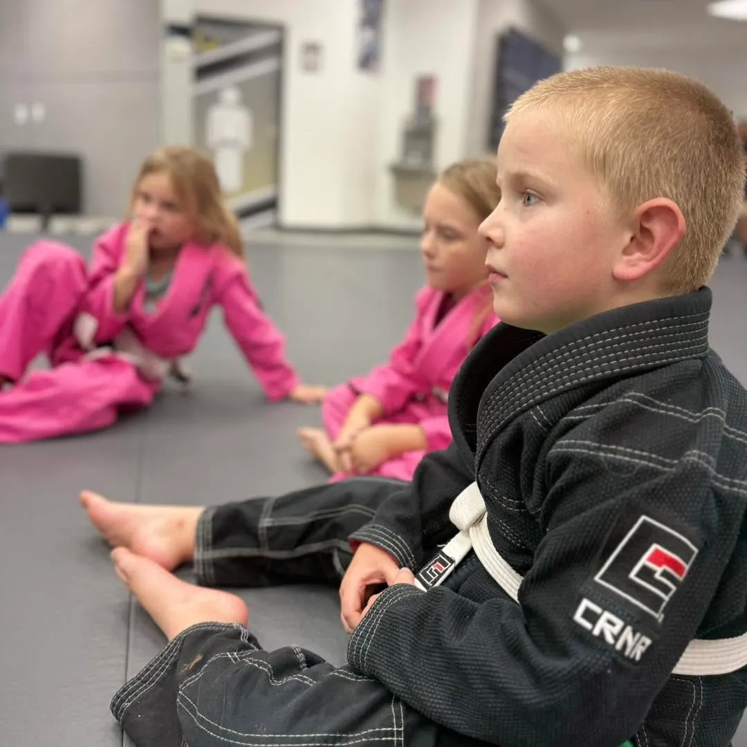 Young student in a black gi listening during class