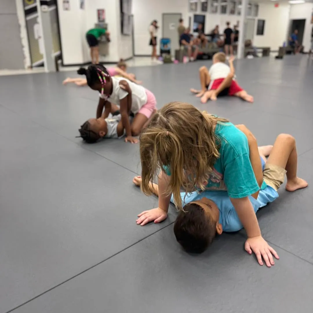 Little kids grappling games on the mats