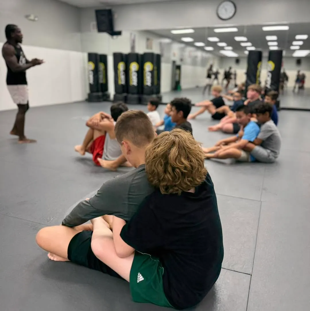 Kids seated on the mat listening to their coach